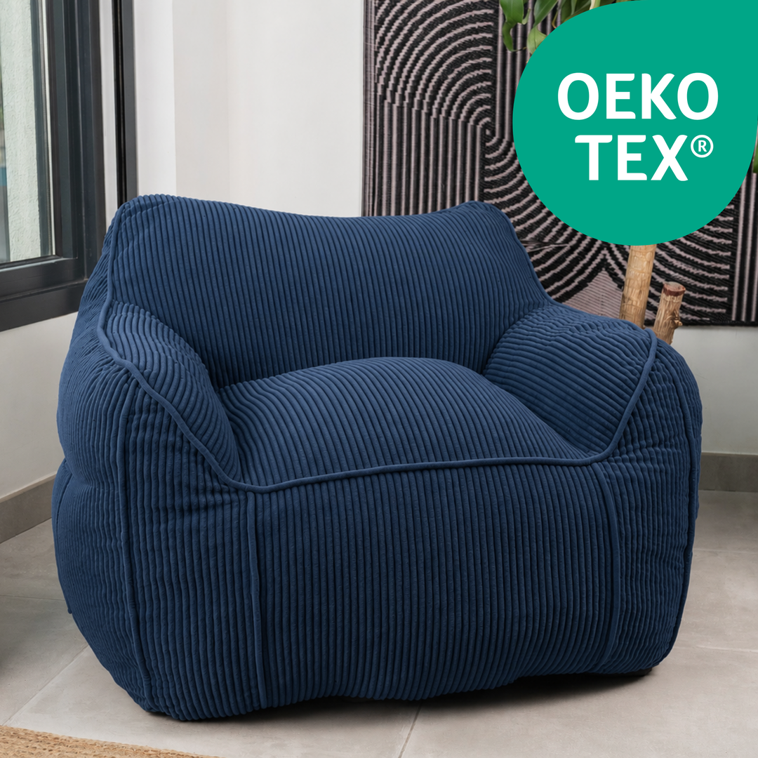 Pouf fauteuil en velours côtelé bleu foncé, dossier haut et assise rembourrée, dans un salon