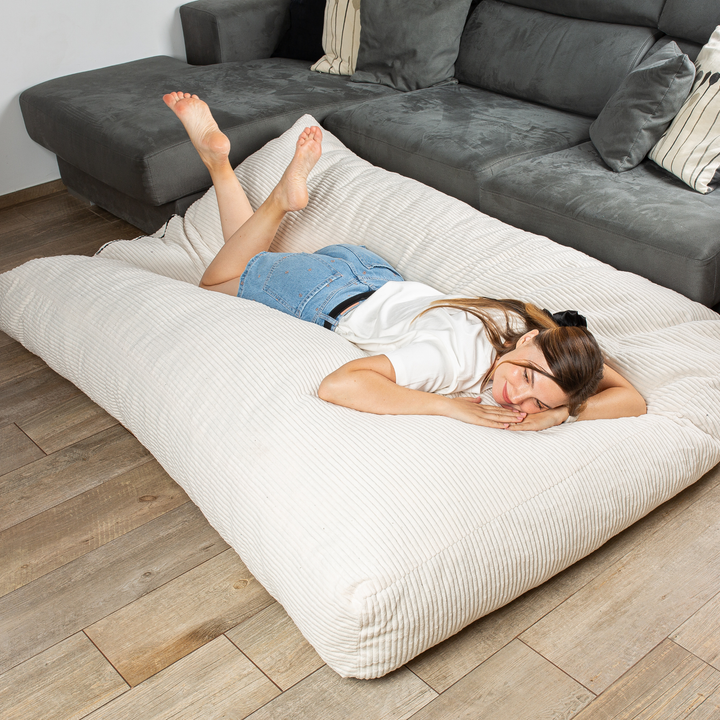 Personne allongée sur le pouf-lit convertible 2en1, utilisé en couchage pour se détendre