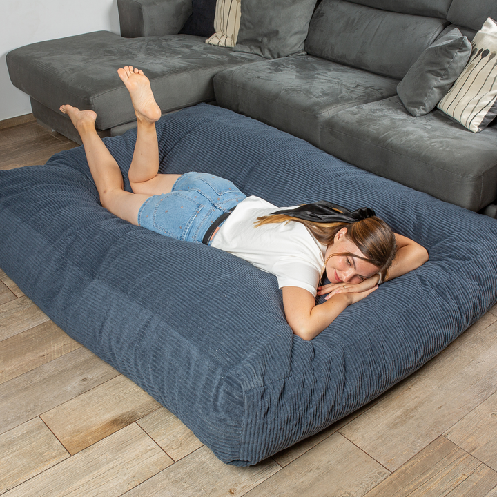 Personne allongée sur le pouf-lit convertible 2en1, utilisé en couchage pour se détendre