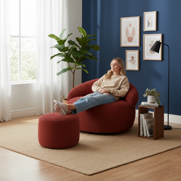 Personne assise confortablement sur un pouf XXL en velours côtelé avec repose-pieds, dans un salon