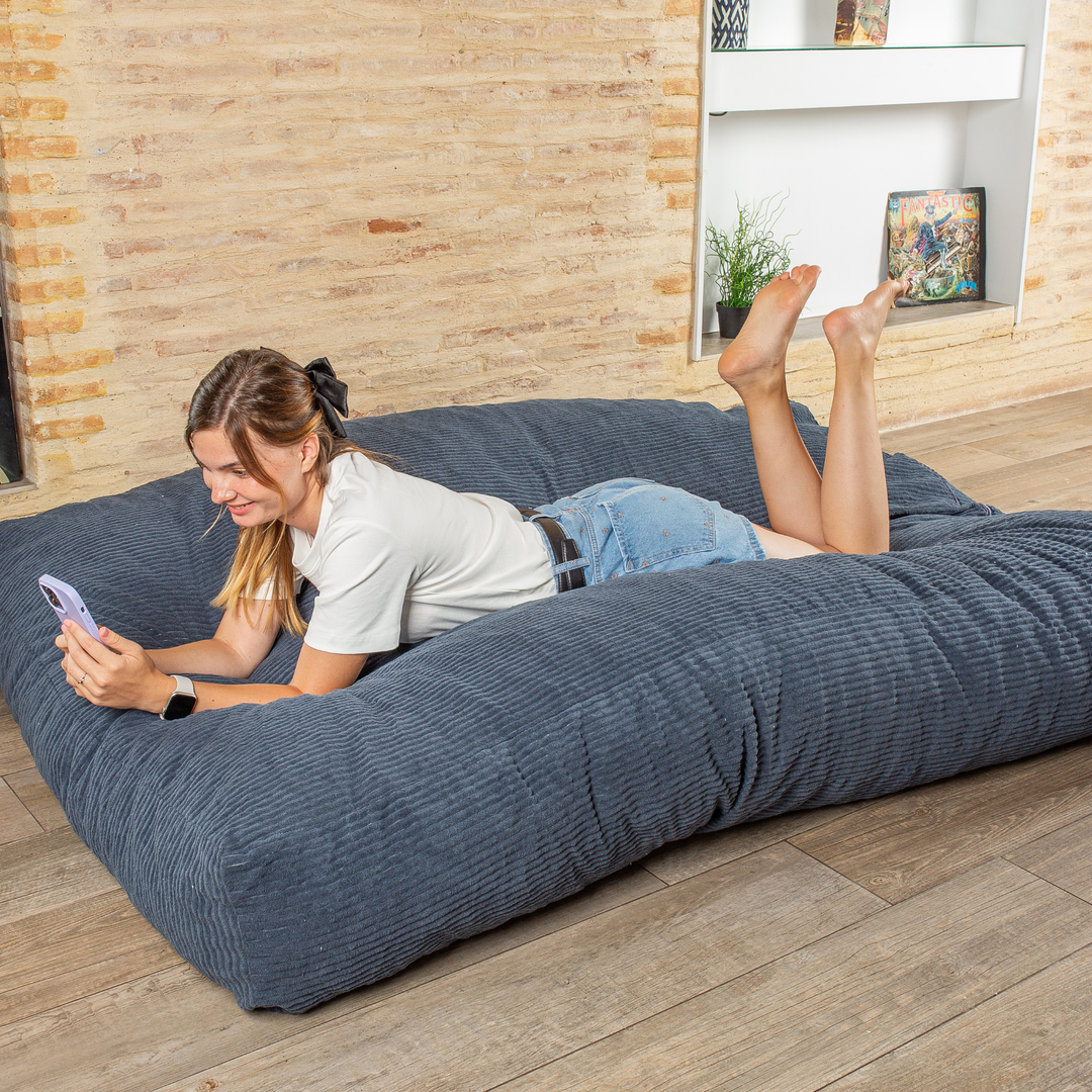 Personne allongée sur le pouf-lit convertible 2en1, utilisé en couchage pour se détendre