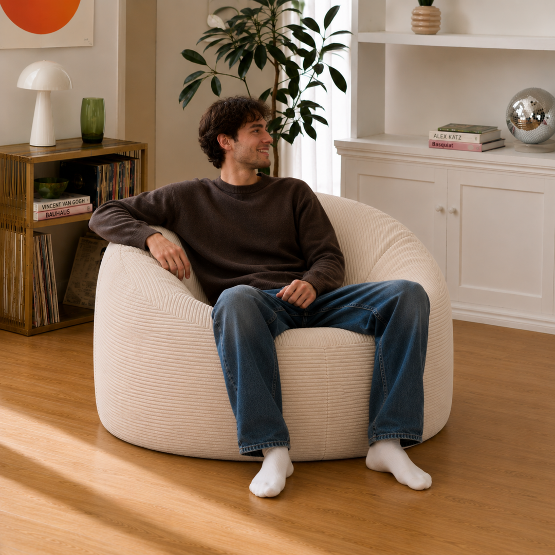 Homme assis sur un pouf déhoussable en velours côtelé épais, assise détendue sur le pouf