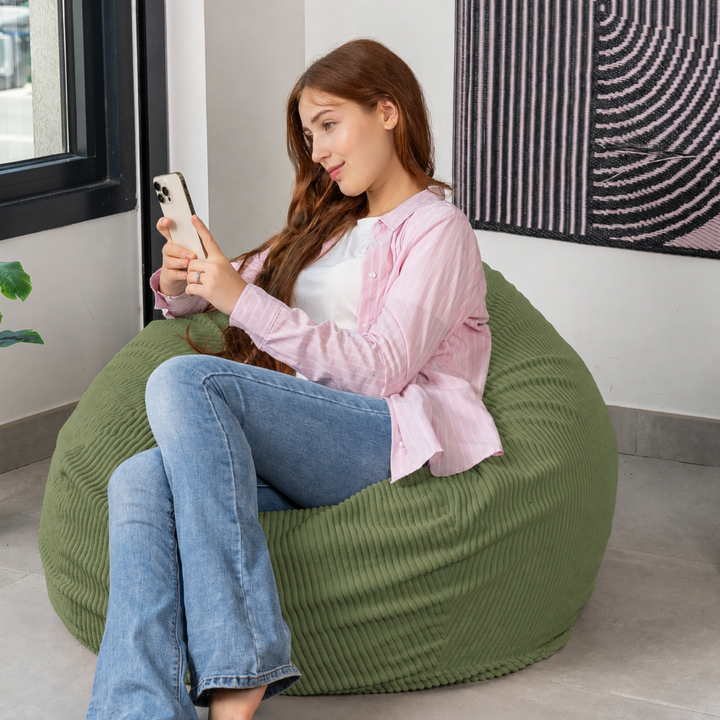 Femme assise sur un pouf poire déhoussable en velours côtelé, dans un salon