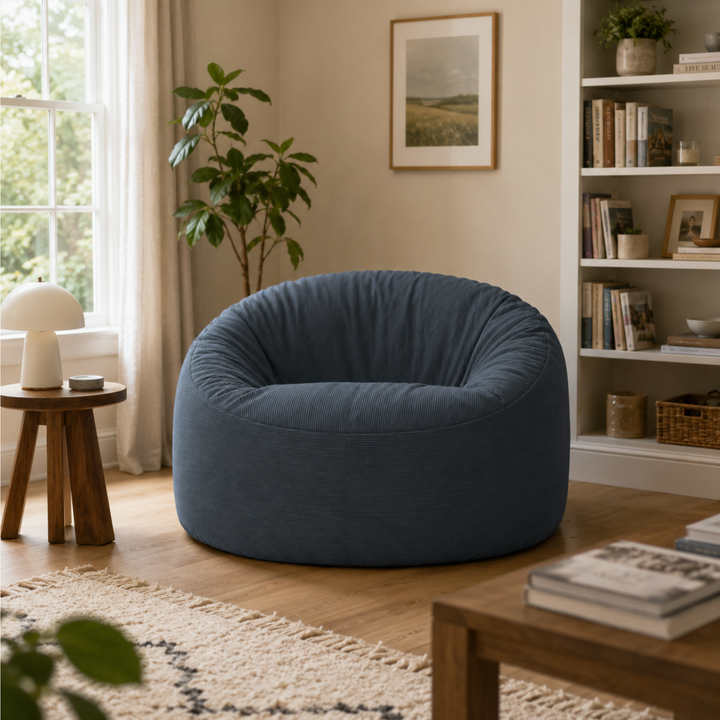 Pouf rond en velours côtelé bleu nuit, assise épaisse et dossier arrondi, dans un salon