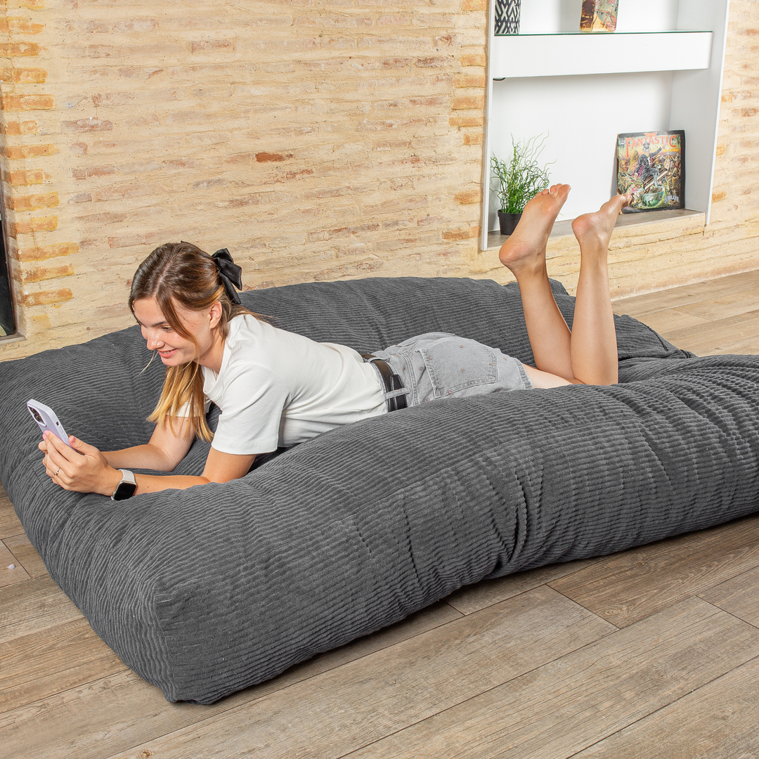 Personne allongée sur le pouf-lit convertible 2en1, utilisé en couchage pour se détendre
