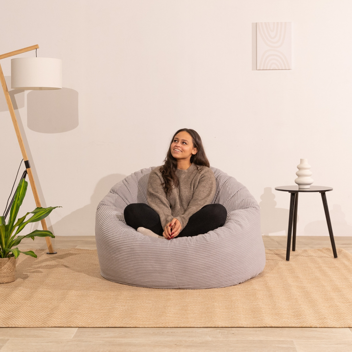 Personne assise confortable sur un pouf en velours côtelé épais