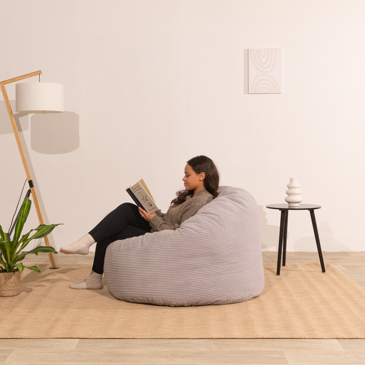 Personne assise confortable sur un pouf en velours côtelé épais