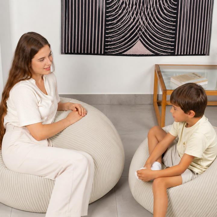 Femme et enfant chacun assis sur un pouf poire déhoussable en velours côtelé, dans un salon.