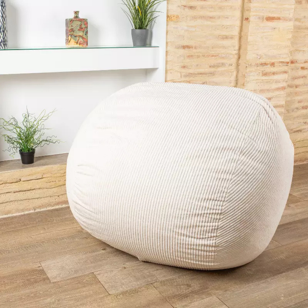 Pouf-lit convertible blanc cassé en position assise, tissu velours côtelé, dans un salon